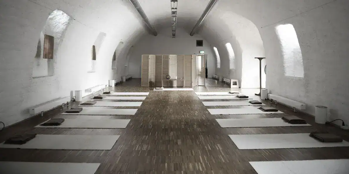 Heller Gewölberaum im Benediktushof mit Matten und Meditationskissen